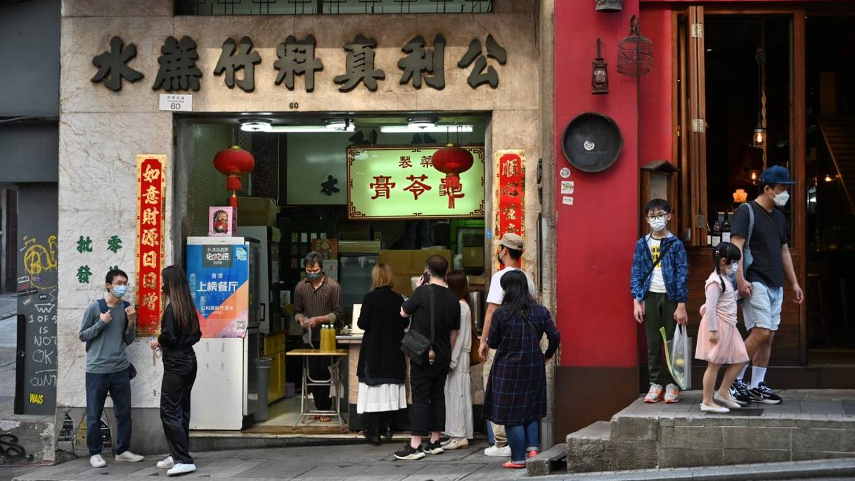 Des personnes font la queue dans un magasin de thé dans une rue de Hong Kong, le 13 mars 2022. 
