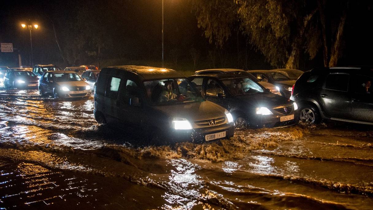 Des véhicules circulent lentement dans les eaux boueuses d'une crue entre Salé et Rabat, le 23 février 2017.
