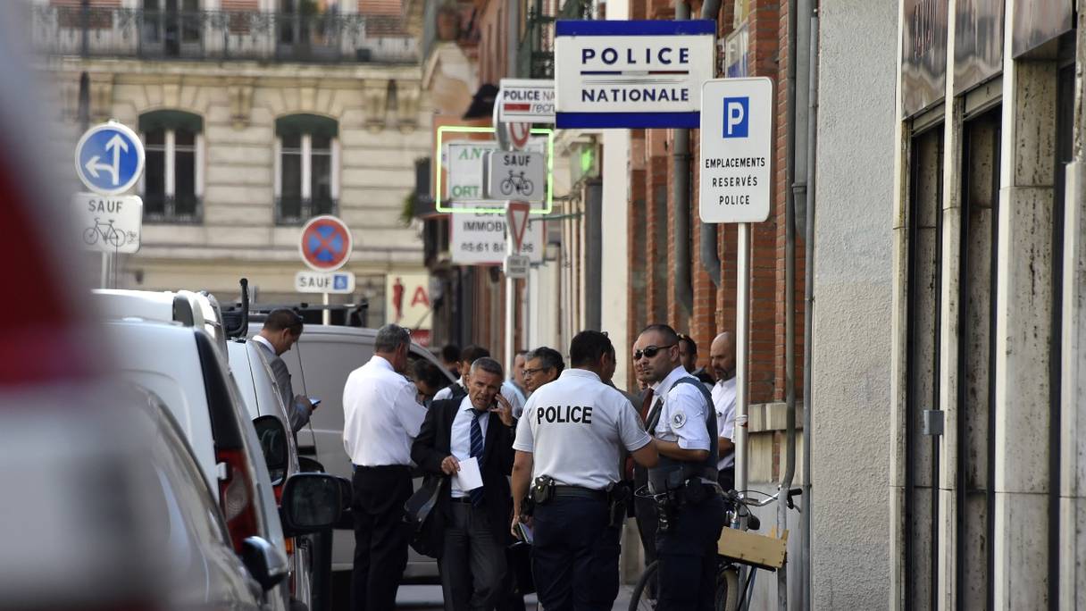 Le procureur français de Toulouse, Pierre-Yves Couilleau (au centre) parle au téléphone en passant devant des policiers français, devant un poste de police où un policier a été poignardé plus tôt dans la journée à Toulouse, le 30 août 2016.
