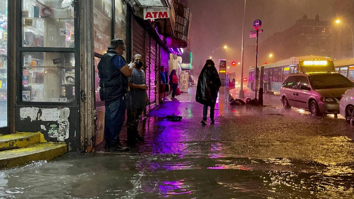 Des personnes se frayent un chemin dans les précipitations des restes de l'ouragan Ida le 1er septembre 2021, dans le quartier du Bronx à New York. L'ouragan a traversé New York, déversant des trombes de pluie en l'espace d'une heure à Central Park.
