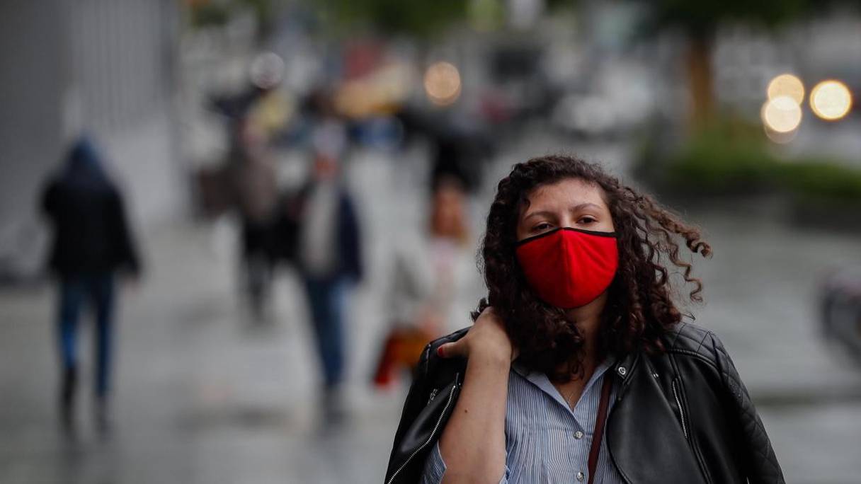 Une femme portant un masque sanitaire dans une rue fréquentée. 
