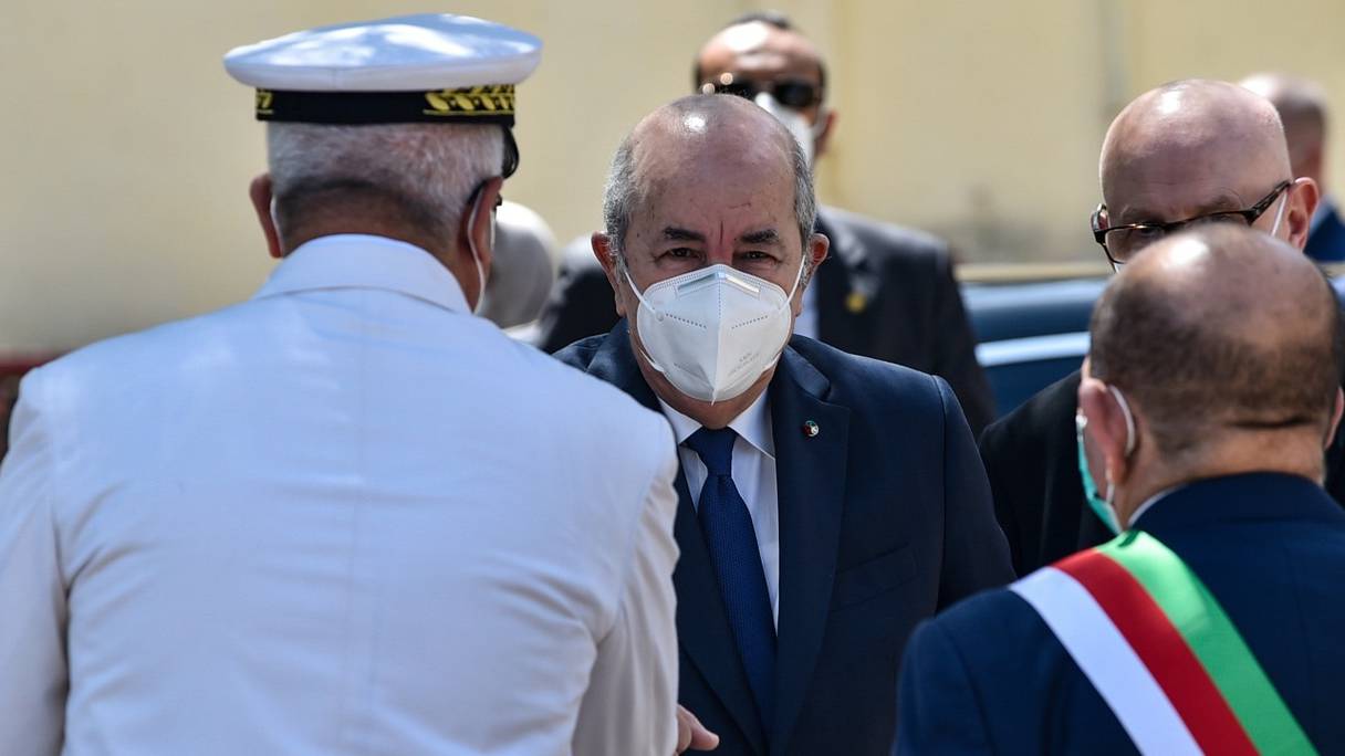 Le président algérien Abdelmadjid Tebboune, ici salué par un officier de l'armée, porte un masque sanitaire à Bouchaoui, dans la banlieue ouest d'Alger, le 12 juin 2021.
