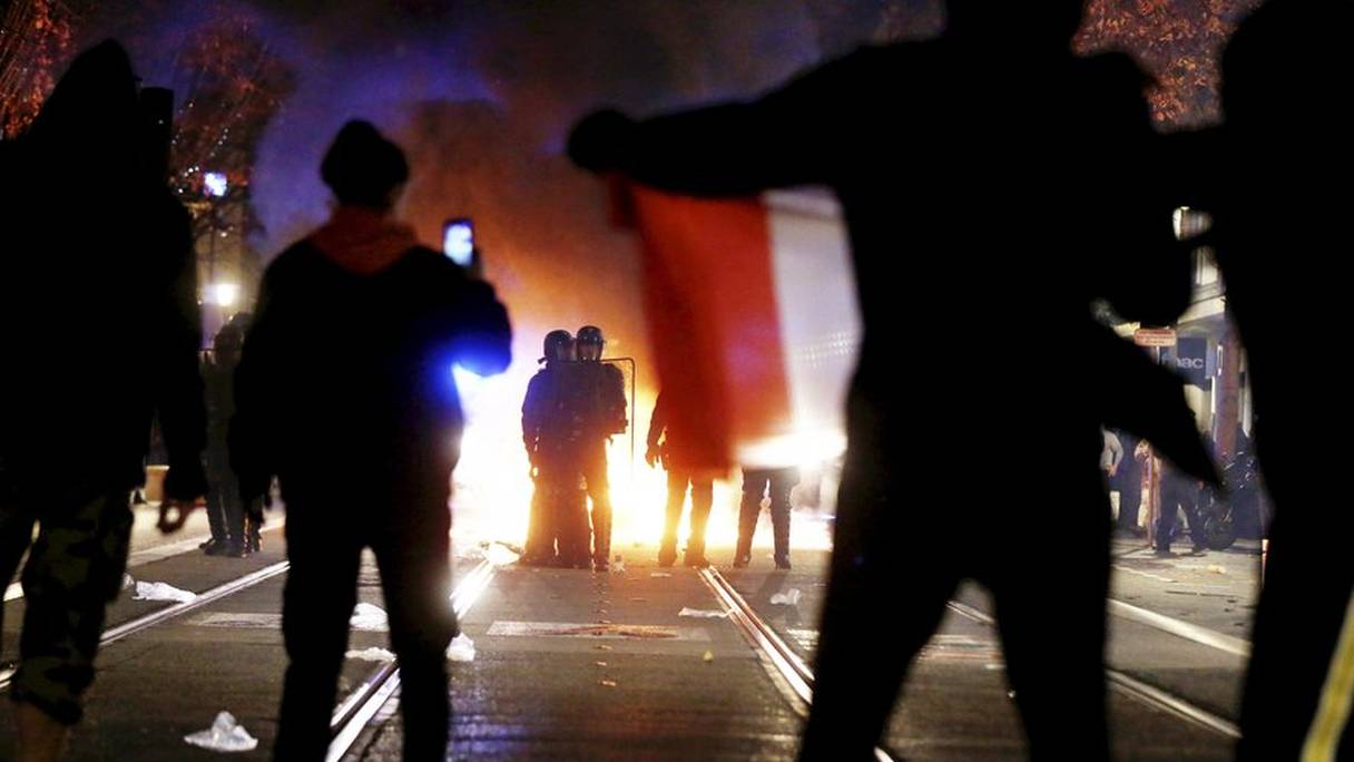 Des manifestants font face à la police française et filment les agents avec des téléphones portables.
