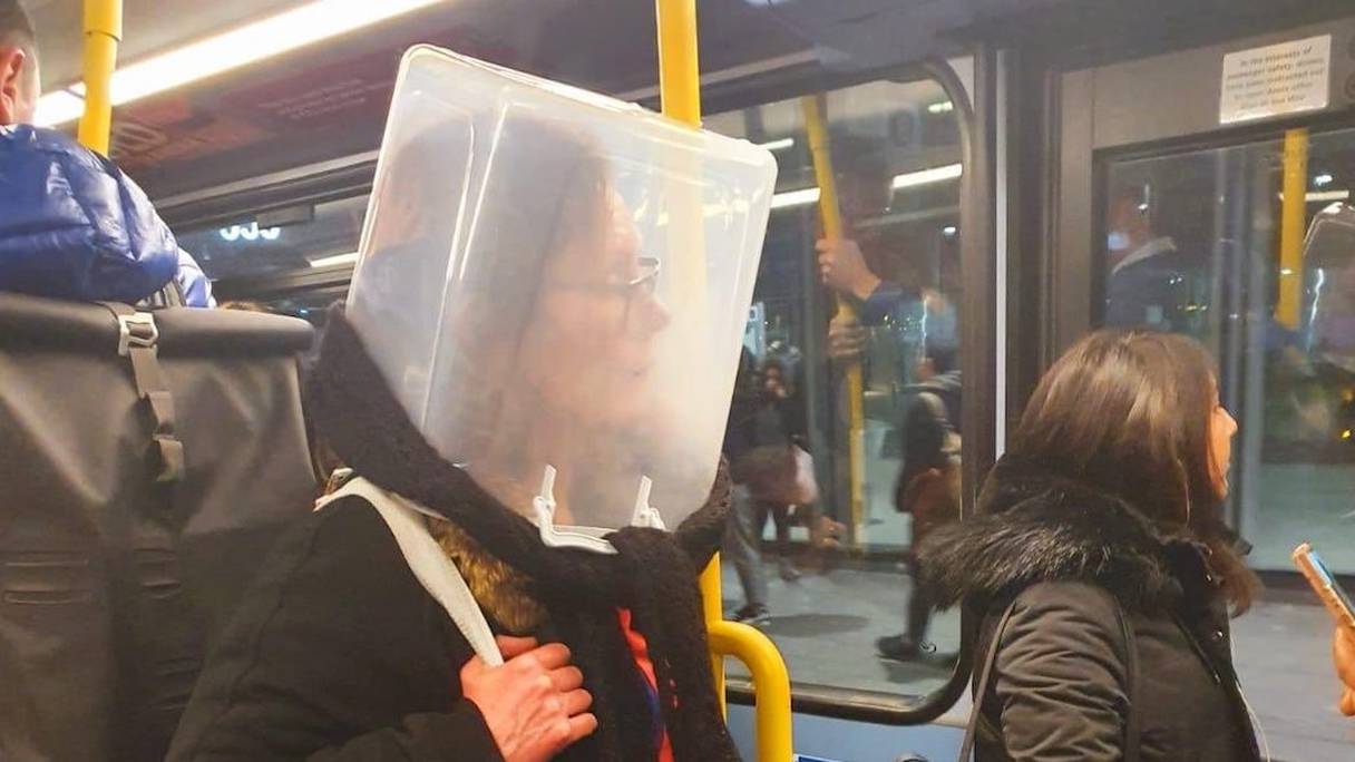 Exit le masque sanitaire: une londonienne se protège du virus dans le métro avec une boîte de rangement en plastique. 
