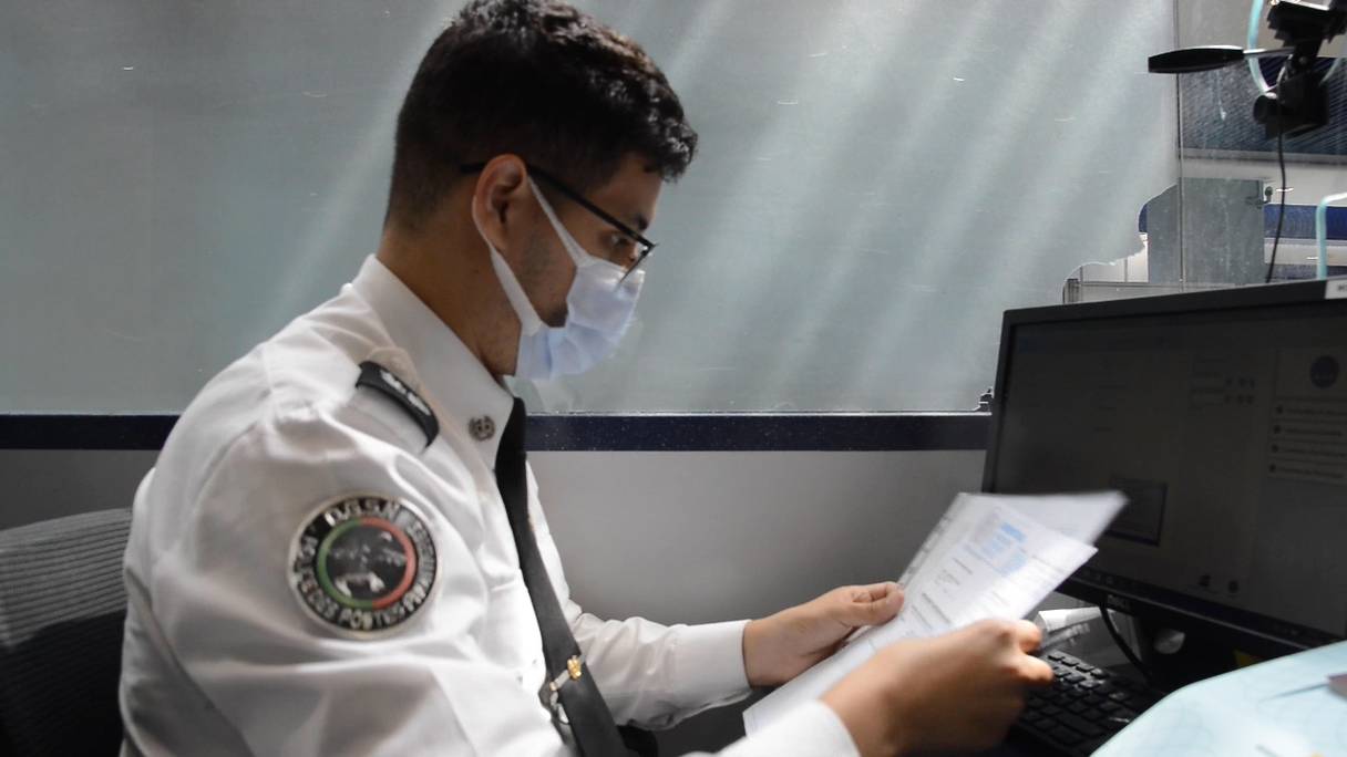 Un policier contrôle les documents sanitaires de voyageurs à l'aéroport Mohammed V de Casablanca, le 4 septembre 2021. 
