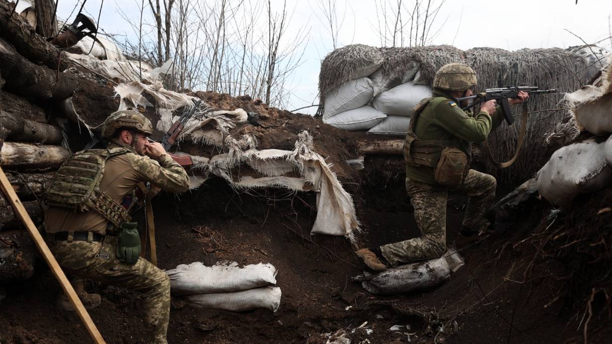 Des soldats ukrainiens tirent avec des fusils d'assaut dans une tranchée sur la ligne de front avec les troupes russes, dans la région de Lougansk, le 11 avril 2022.
