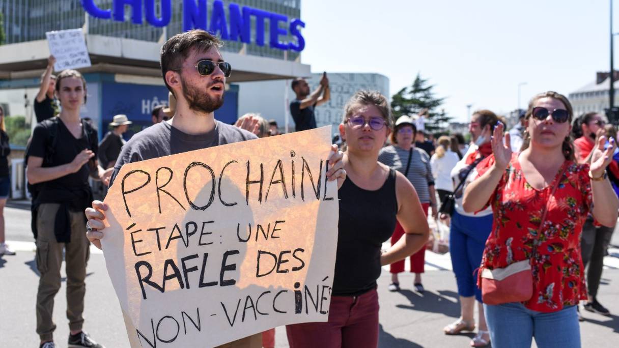 Un manifestant tient une pancarte dénonçant les nouvelles mesures de sécurité contre le Covid-19, y compris un laissez-passer sanitaire obligatoire demandé par le gouvernement français, à Nantes, dans l'ouest de la France, le 17 juillet 2021.
