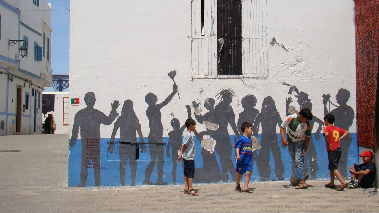 Des enfants devant une fresque qui les représente, à Chefchaouen. 
