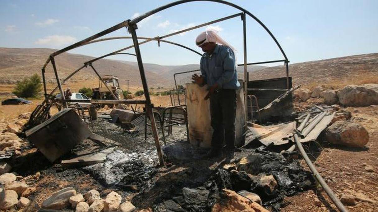 Un bédouin observe le 13 août 2015 à Ein Samiya, en Cisjordanie occupée, l'abri de stockage détruit par un incendie.
