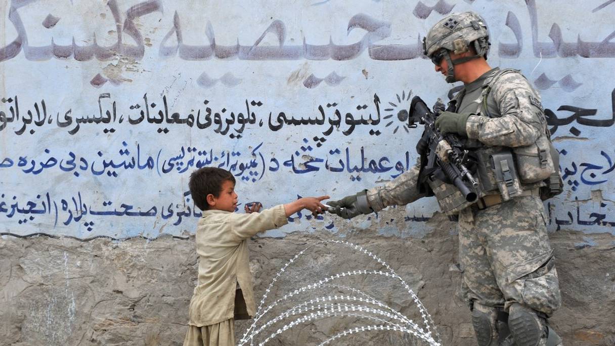 Un soldat américain de la 4e division d'infanterie 4e brigade Alpha Company donne un cadeau à un enfant afghan lors d'une patrouille à Khogyani, à Nangarhar, le 20 février 2010. 
