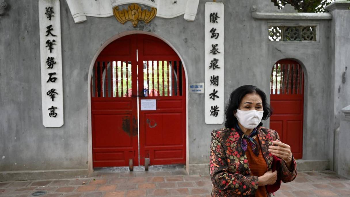 Une femme marche à l'extérieur du temple Ngoc Son, fermé en raison des restrictions du coronavirus Covid-19, à Hanoï, au Vietnam, le 17 février 2021.
