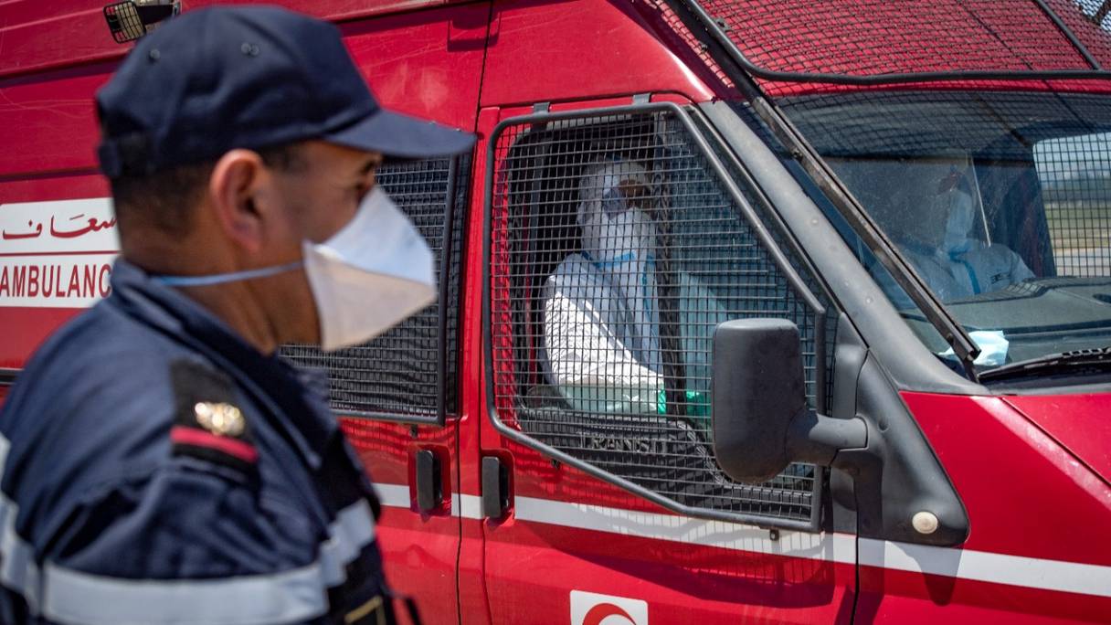 Un membre des équipes médicales marocaines attend des cas de Covid-19 à bord d'une ambulance de la protection civile, dans un parking de la ville de Moulay Bousselham, au nord de Rabat, le 20 juin 2020.

