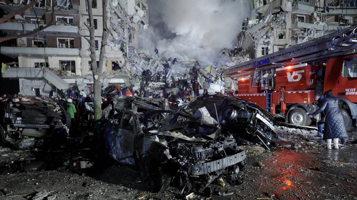 Des voitures et des immeubles résidentiels détruits par une frappe mortelle de missile contre un immeuble résidentiel dans la ville de Dnipro, dans l'est de l'Ukraine, le 14 janvier 2023.
