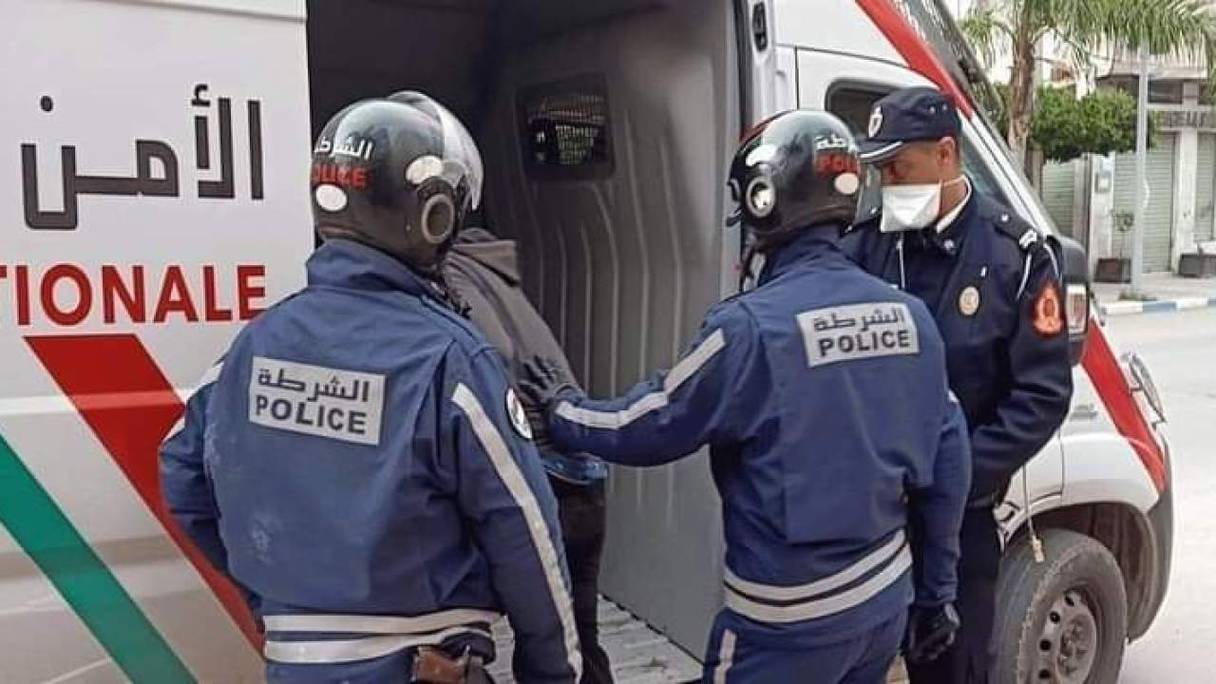 Trois agents de police font entrer une personne dans une fourgonnette de la Sûreté Nationale, au Maroc. 
