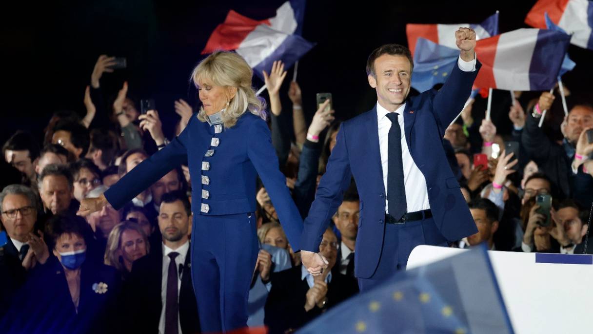 Réélu pour un second mandat, Emmanuel Macron lève le poing et tient la main de son épouse, Brigitte Macron, après sa victoire à l'élection présidentielle française, au Champ de Mars à Paris, le 24 avril 2022.
