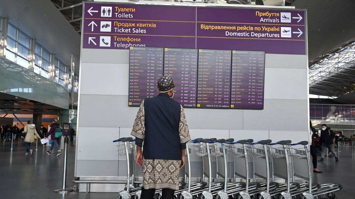 Un homme regarde le tableau des départs, à l'aéroport de Boryspil, à environ 30 kilomètres de Kiev, le 13 février 2022.
