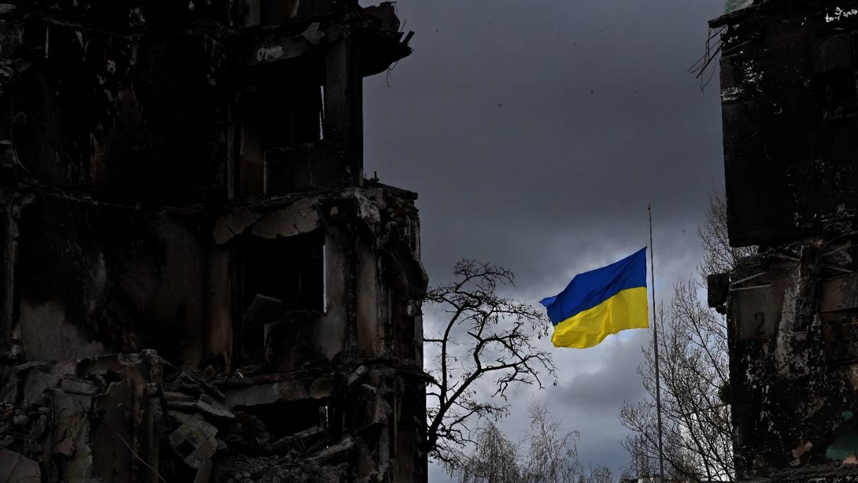 Le drapeau ukrainien flotte entre des bâtiments détruits lors d'un bombardement, dans la ville ukrainienne de Borodianka, dans la région de Kiev, le 17 avril 2022. La Russie a envahi l'Ukraine le 24 février 2022.
