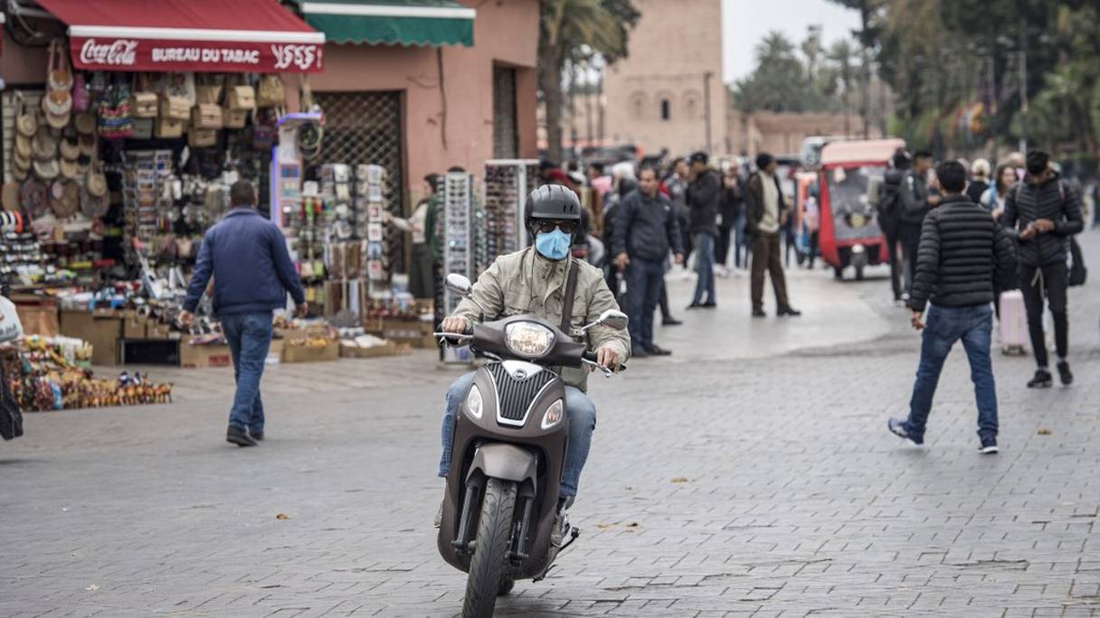 Un homme, sur sa motocyclette, porte un masque de protection contre le coronavirus, à Marrakech.
