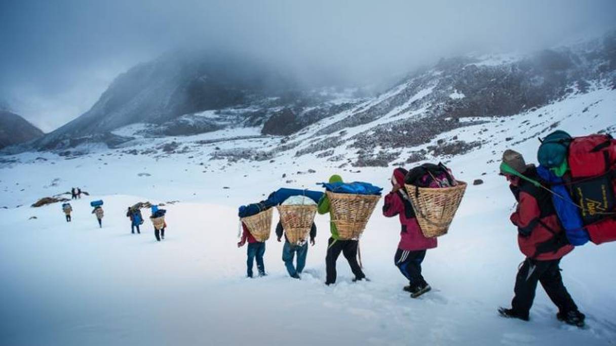 Des sherpas transportant tout le matériel de montagne nécessaire pour les grimpeurs.

