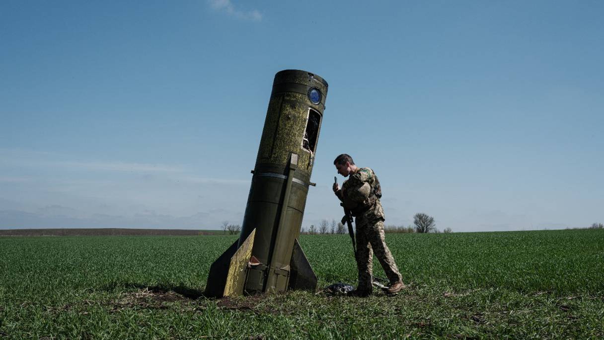 Un militaire ukrainien regarde l'étage d'appoint d'un missile balistique russe, tombé dans un champ à Bohodarove, dans l'est de l'Ukraine, le 25 avril 2022.
