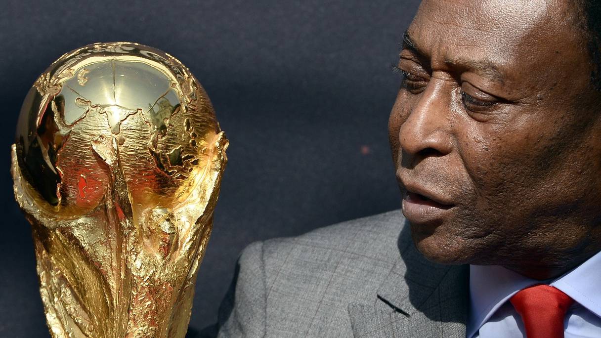 La légende du football brésilien Pelé contemple le trophée de la Coupe du Monde, au cours d'un événement de la FIFA, devant l'Hôtel de Ville, à Paris, le 9 mars 2014 -archives.
