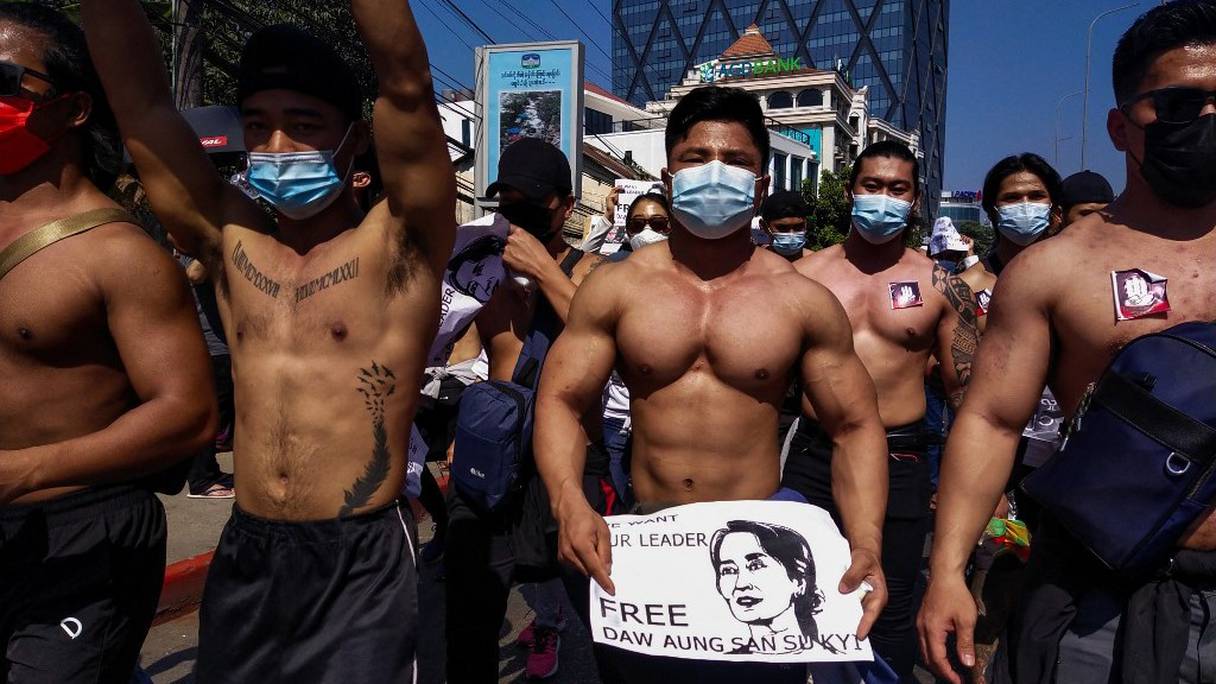 Des hommes torse nu tiennent des pancartes appelant à la libération de la dirigeante détenue de Birmanie, Aung San Suu Kyi, et défilent lors d'une manifestation contre le coup d'Etat militaire à Rangoon, le 10 février 2021.
