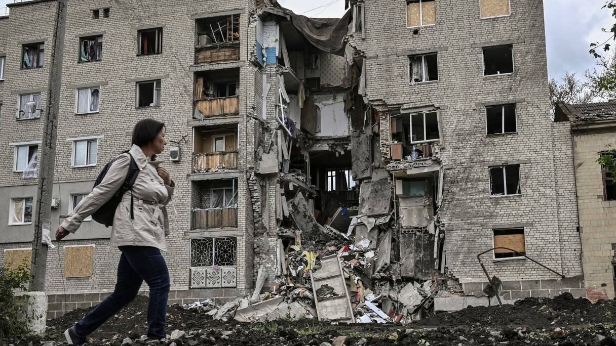 Une femme passe devant un immeuble détruit à Bakhmut dans la région ukrainienne orientale du Donbass le 22 mai 2022.
