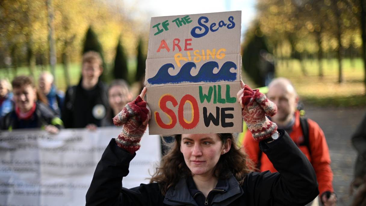 Une femme brandit une pancarte au cours d'une action directe non violente organisée par le groupe d'action militant Extinction Rebellion, à Glasgow, en Ecosse, le 30 octobre 2021. La Conférence des Nations Unies sur le changement climatique -COP26- s'y tient à partir du 31 octobre.

