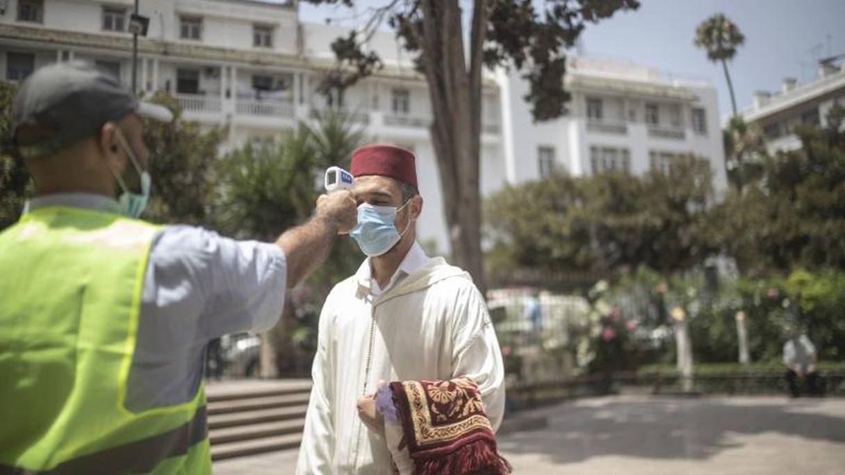 Un agent de sécurité prend la température d'un fidèle, venu prier à la mosquée Hassan, dans le centre de Rabat, le 15 juillet 2020.
