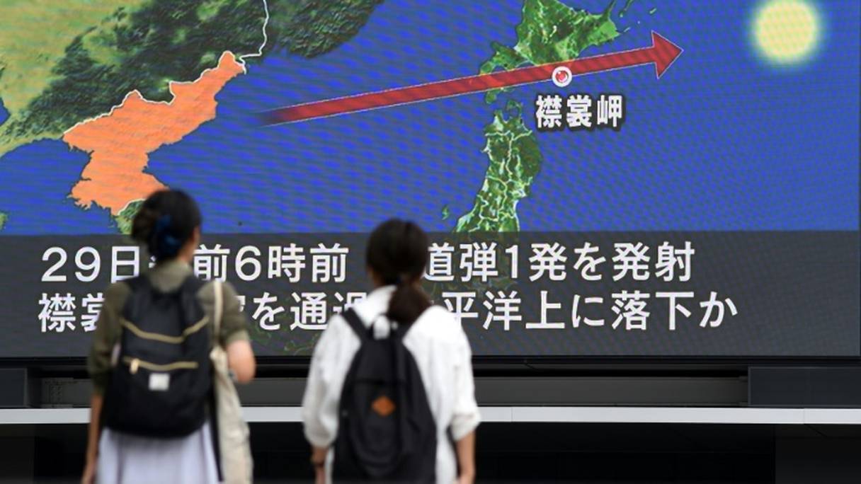 Des passants regardent le 29 août 2017 à Tokyo un écran montrant la carte du Japon et de la péninsule coréenne, d'où est parti le missile qui a survolé l'archipel.

