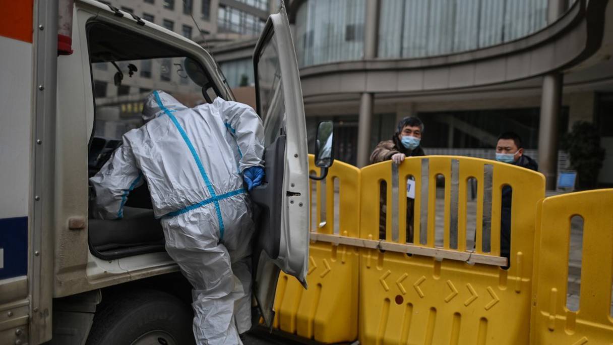 Un travailleur équipé d'une combinaison monte à bord de son camion, devant une barrière près de l'hôtel où l'équipe de l'OMS enquêtant sur les origines de la pandémie termine sa quarantaine, à Wuhan, en Chine, le 28 janvier 2021.
