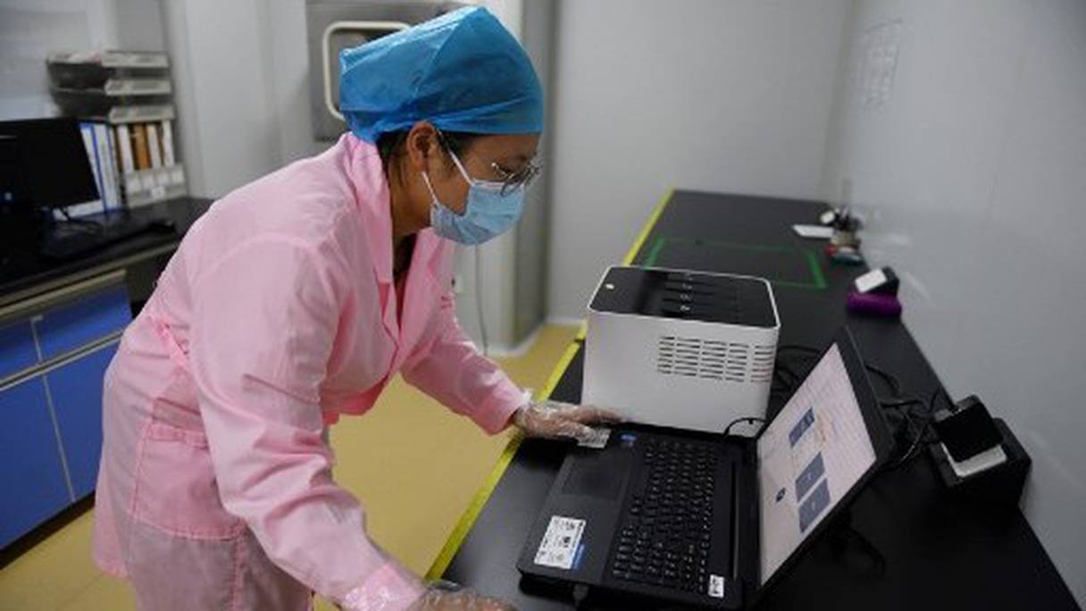 Une technicienne vérifie les résultats d'un test en utilisant le "Flash 20", une machine conçue par l'entreprise chinoise de biotechnologie Coyote pour réaliser des dépistages rapides au nouveau coronavirus, le 27 septembre 2020 à Pékin. 
