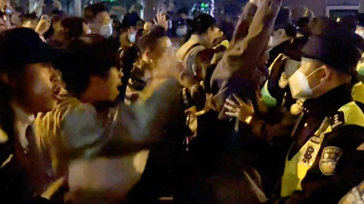 Des manifestants crient des slogans hostiles à la politique radicale zéro-Covid du gouvernement, alors que la police tient ses positions, à Shanghai, en Chine, le 27 novembre 2022.
