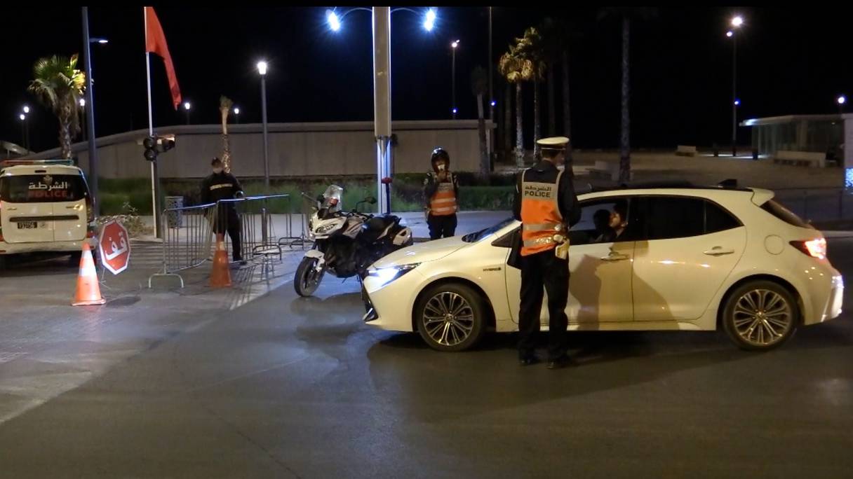 Un agent de police contrôle un automobiliste, dans un barrage à Casablanca, au cours de la nuit du 3 août 2021, dans le contexte de l'entrée en vigueur d'un couvre-feu de 21 heures à 5 heures du matin.
