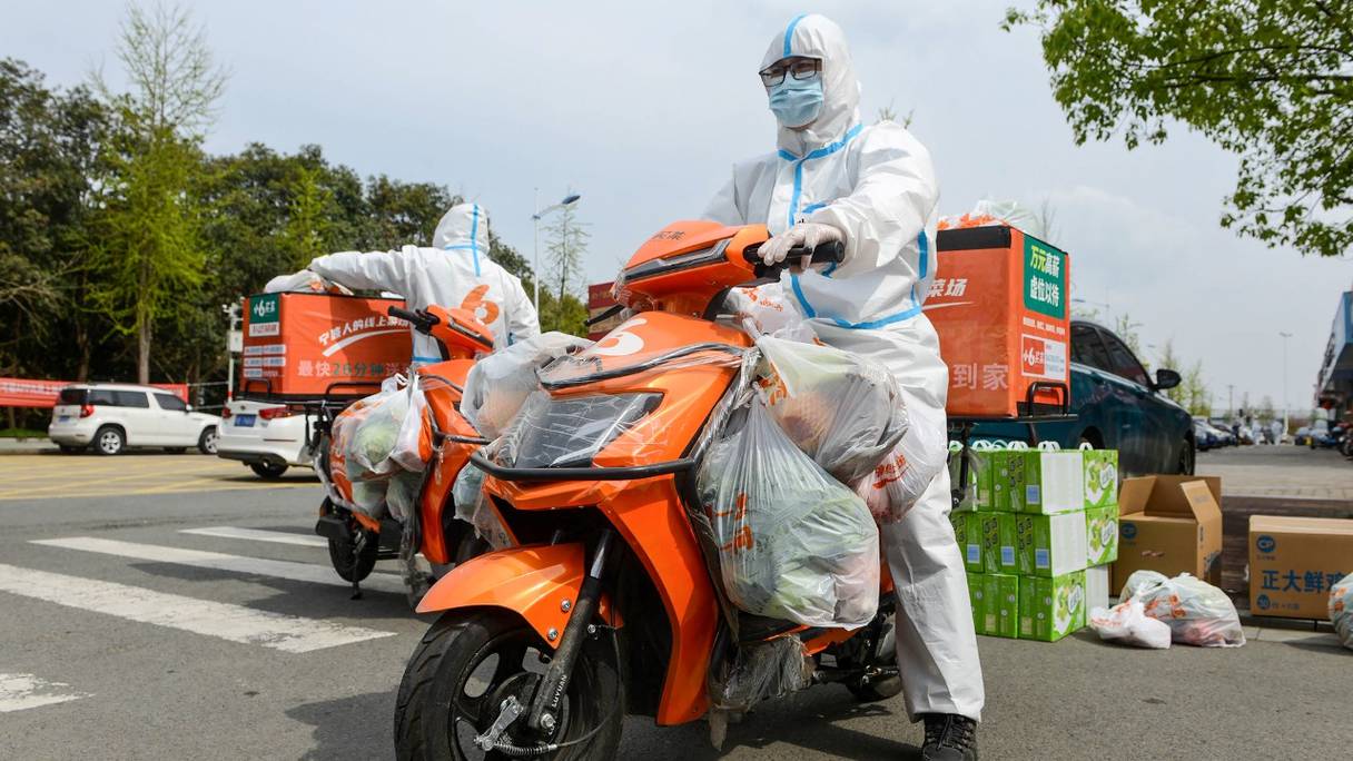 Un livreur portant un équipement de protection individuelle va livrer de la nourriture achetée en ligne aux résidents qui ont été confinés en raison d'une récente épidémie de Covid-19, à Ningbo, dans la province orientale du Zhejiang, en Chine, le 2 avril 2022.

