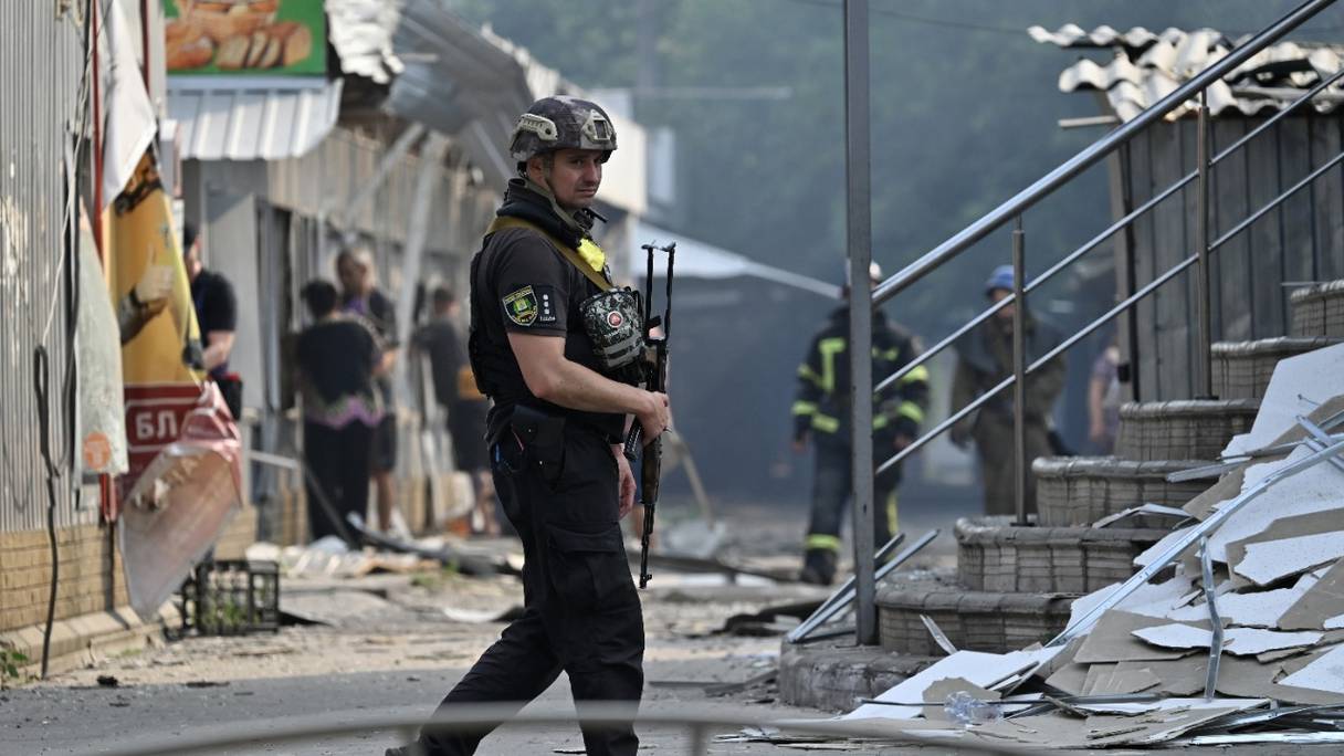 Un policier ukrainien patrouille devant des magasins détruits dans un marché, après une attaque à la roquette dans la ville ukrainienne de Sloviansk, le 3 juillet 2022, au cours de l'invasion russe de l'Ukraine.

