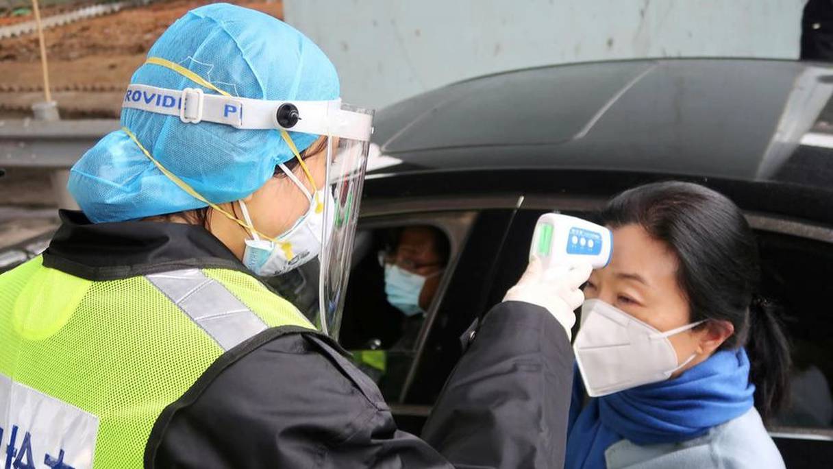 Dans la ville de Xianning, province du Hubei, un agent des services sanitaires teste la température d'une habitante avec une caméra thermique. 
