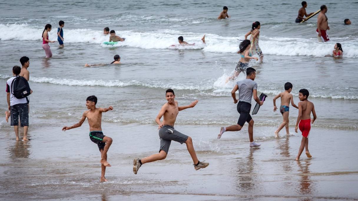 De jeunes baigneurs s'amusent sur une plage le long de la côte de la ville de Salé, au nord de Rabat, le 25 juin 2020.
