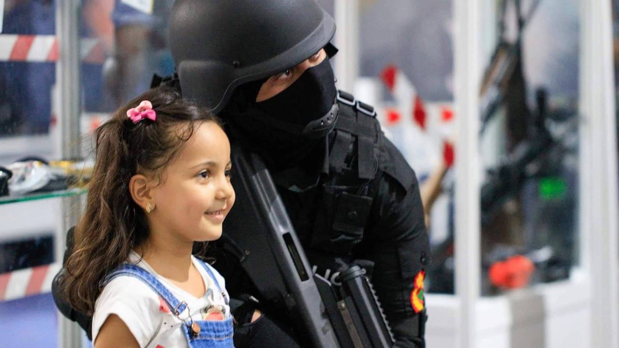 Une petite fille se fait prendre en photo avec un agent des forces d'intervention de la DGSN.
