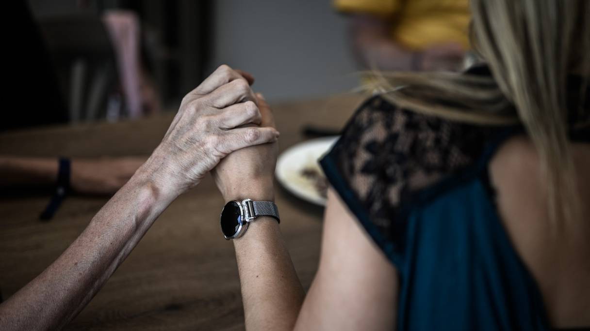 Un volontaire (à droite) tient la main d'un malade d'Alzheimer pendant le déjeuner dans une maison de retraite pour patients atteints de cette maladie, à Dax, dans le sud-ouest de la France (photo d'archives du 9 septembre 2020).
