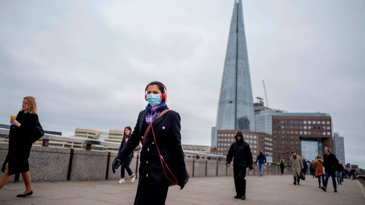 Un travailleur de la City, sur le pont de Londres, enjambant la Tamise, porte un masque de protection contre le coronavirus. 
