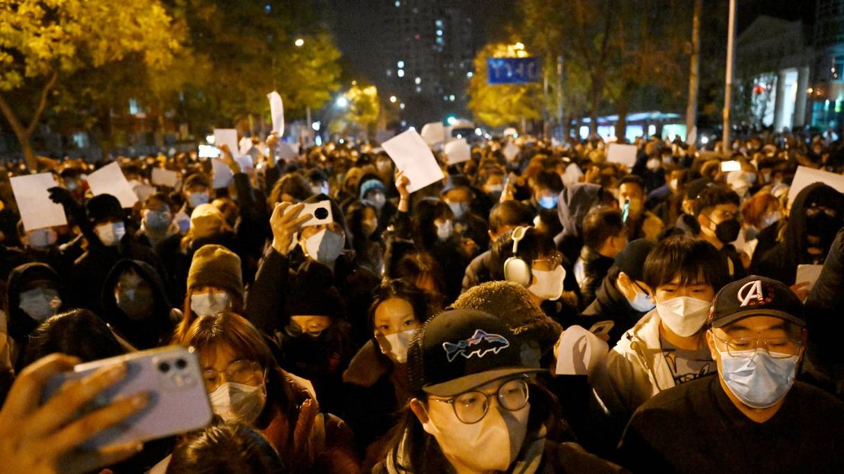 Des manifestants défilent dans une rue, un rassemblement de soutien aux victimes d'un incendie meurtrier à Urumqi (nord-ouest) et de protestation contre les dures restrictions de lutte contre le Covid-19 imposées par la Chine, à Pékin, le 28 novembre 2022.
