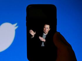 Elon Musk sur un smartphone, et le logo de Twitter à l’arrière-plan, le 4 octobre 2022. Le propriétaire de Twitter a acté le 24 novembre 2022 l’amnistie générale des comptes suspendus, après un sondage informel auquel ont participé 3,16 millions d’utilisateurs.
