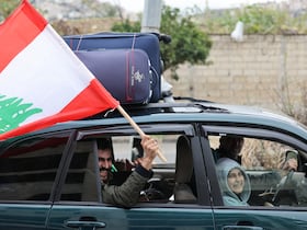 Un homme brandit le drapeau du Liban dans la ville de Sidon, dans le sud du Liban, le 27 novembre 2024, alors que des personnes déplacées rentrent chez elles dans le sud du Liban après l'entrée en vigueur d'un cessez-le-feu entre Israël et le Hezbollah