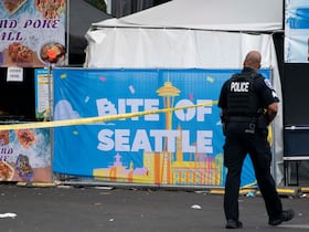 Un policier passe devant une affiche pour le festival culinaire Bite of Seattle, le 26 juillet 2026 à Seattle, dans l'État de Washington. Deux personnes sont mortes et plusieurs autres ont été blessées lors d'une fusillade de masse survenue lors de cet événement dimanche soir, au Seattle Center.
