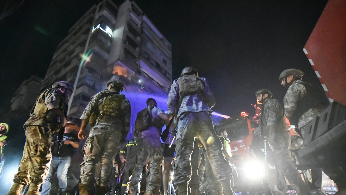 Des soldats de l'armée libanaise sécurisent le site à l'extérieur d'un immeuble touché par une frappe aérienne israélienne dans le quartier de Cola à Beyrouth, le 30 septembre 2024.