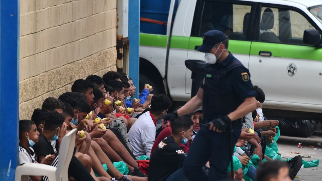Des migrants mineurs mangent des pommes en attendant d'être testés pour le Covid-19, à leur arrivée dans le préside occupé de Sebta, le 19 mai 2021.