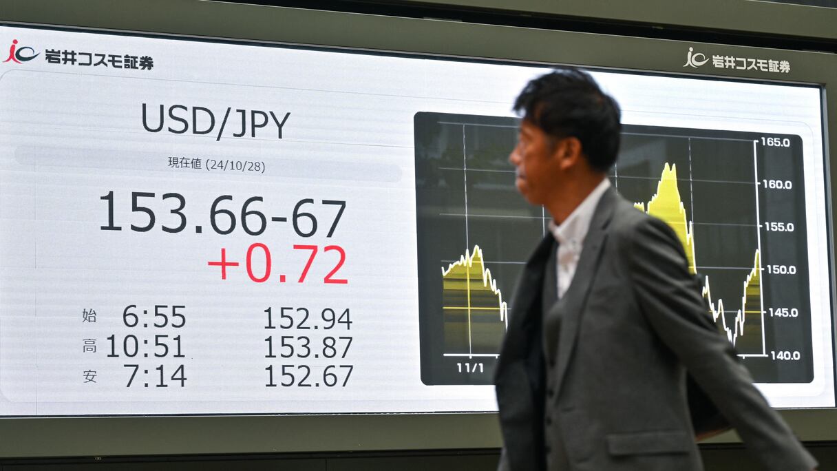 Un homme passe devant un tableau électronique affichant le prix de change du yen japonais par rapport au dollar américain, dans une rue du centre de Tokyo, le 28 octobre 2024
