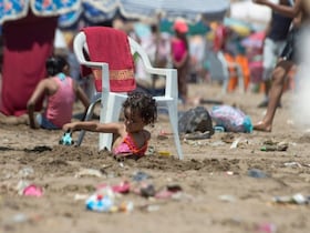 Une petite fille s'amusant sur une plage jonchée de saletés.