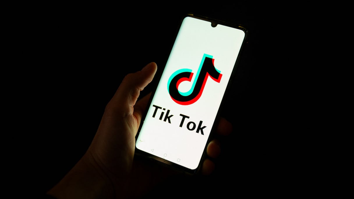 Cette photographie prise le 19 avril 2024 montre un homme tenant un smartphone affichant le logo de la plateforme de médias sociaux chinoise Tiktok dans un bureau à Paris.